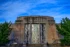 Color photo. The entrance to the Seattle Asian Art Museum, underneath a blue sky full of wispy clouds. The entrance is flanked by statues of seated camels. People sit on the steps leading up to the doors.