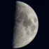 Photo of the surface of the moon, as seen from earth. Half of the moon is visible, covered in craters and mare.