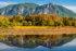 Color photo. Mount Si and a small lake. The mountain is reflected in the lake. Growing on the far shore are a line of trees going golden autumn yellow.