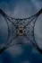 Color photo. A lattice with curving edges. The supports cross diagonally and, in the center, is a golden ring. The background is a mottled dark blue and grey.